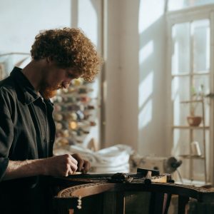 Handwerker restauriert ein antikes Moebelstueck in einer hellen Werkstatt